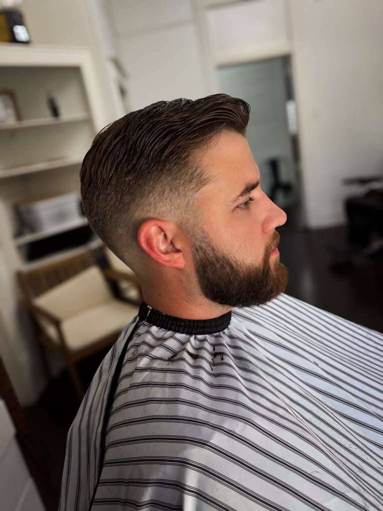 Man with dark hair and beard in profile wearing a striped shirt in a modern interior space